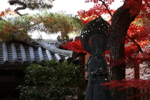 Ancient statue amidst vibrant red maple leaves and temple roof. jigsaw puzzle