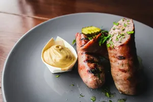 two sausages on a plate with mustard on the side jigsaw puzzle