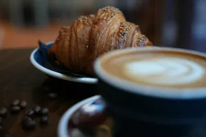 Croissant and latte with coffee beans on table jigsaw puzzle