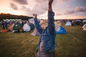 a woman raising her arms in the air in front of tents jigsaw puzzle