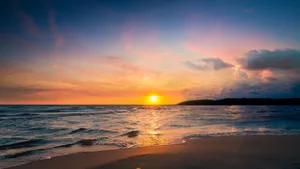 Serene beach view at sunset with vibrant sky reflecting on the water. jigsaw puzzle