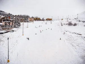 Diverse skiers enjoying a winter day on a snowy slope in a picturesque village. jigsaw puzzle
